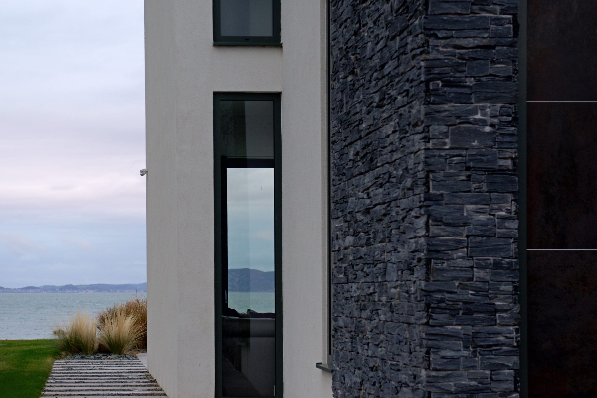 a white building with a black door next to a body of water.